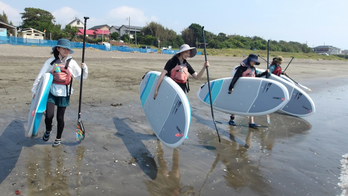 ボードを抱えて海へ向かう参加者たち（SUP体験）