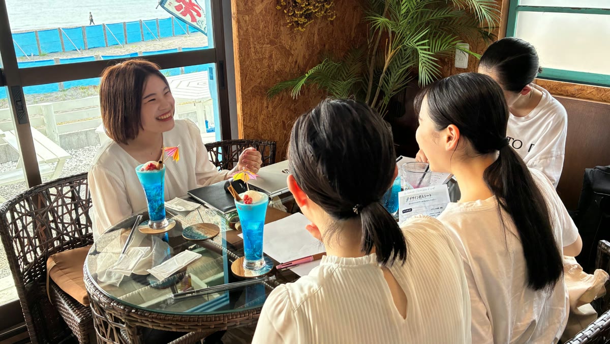 海辺のカフェで先輩社員と就活について語り合う参加者たち