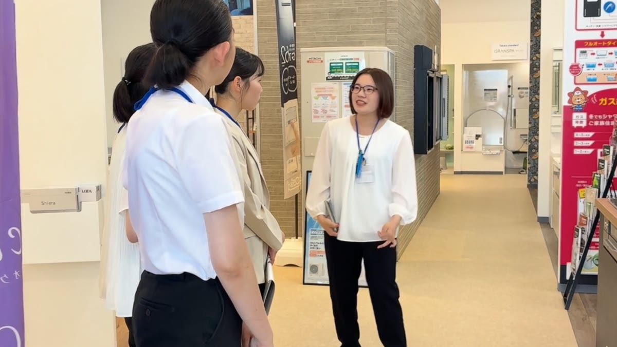 ショールームで社員の説明を聞く参加者たち